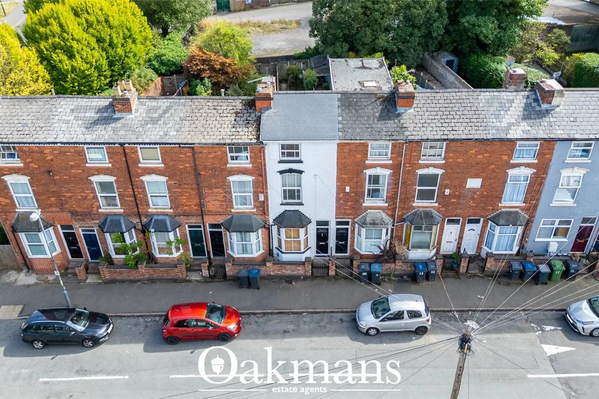 Aerial view of Victorian terraced brick townhouses with slate roofs, sash windows and front doors, parked cars on street