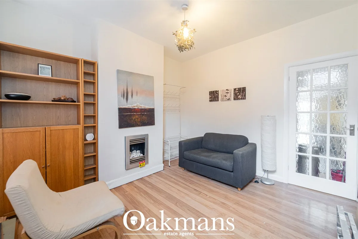 Bright living room with dark grey sofa, wooden shelving unit, fireplace with artwork, pendant light, and glass doors to 