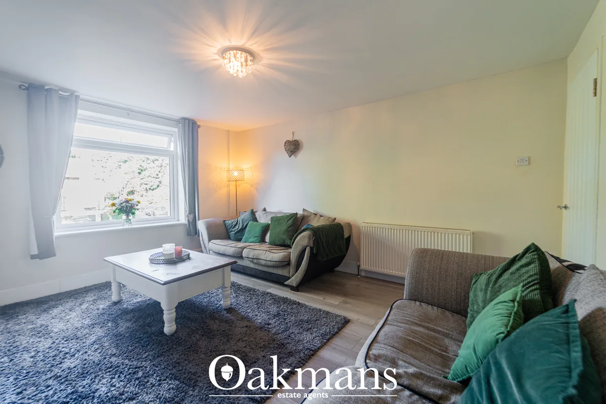 Bright living room with grey sofa, green cushions, white coffee table, large window with countryside views, radiator and