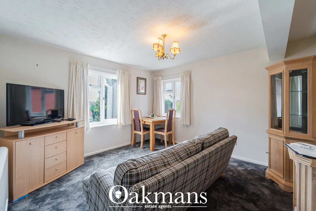 Spacious living room with plaid sofa, wooden furniture, flat-screen TV, dining table, large windows with views, and crea