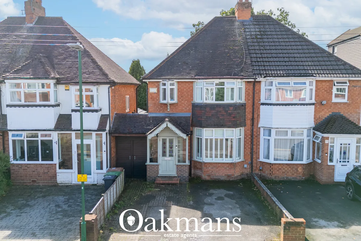 Row of detached brick houses with slate roofs, white-framed windows, driveways and garages on residential street