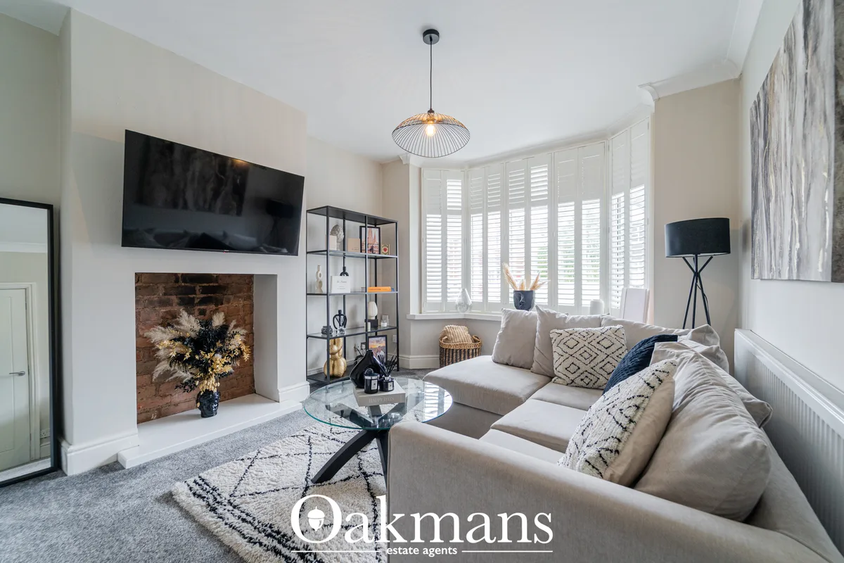 Contemporary living room with cream sofas, fireplace with dark surround, wall-mounted TV, pendant light, shuttered windo