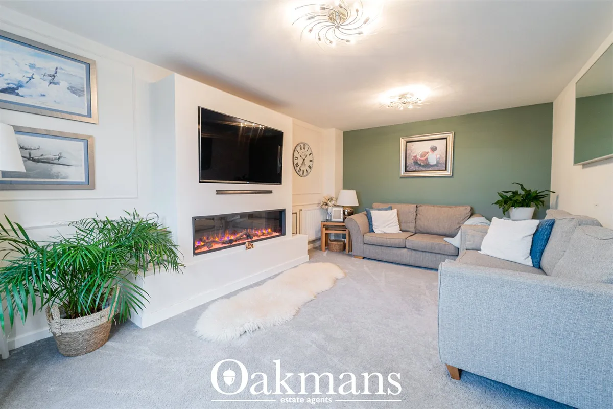 Spacious living room with two grey sofas, electric fireplace, wall-mounted TV, green accent wall, artwork and decorative