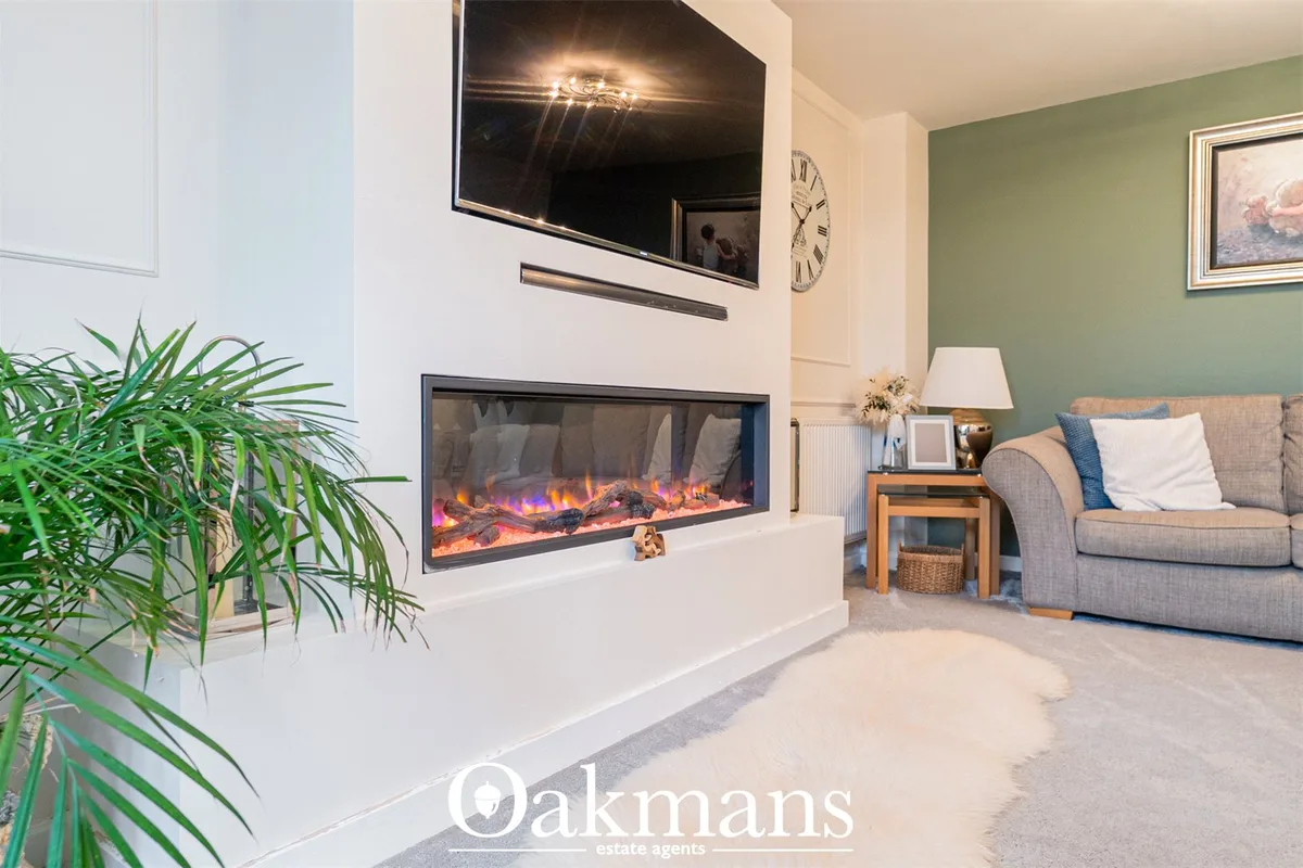 Spacious living room with feature fireplace, wall-mounted TV, cream sofa with blue cushions, green accent wall, wooden s