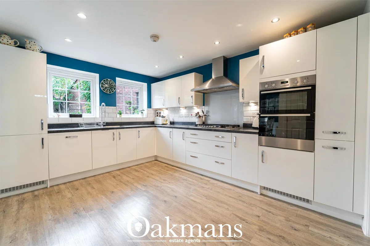 Modern fitted kitchen with white gloss units, black granite worktops, stainless steel appliances, blue feature walls, wo