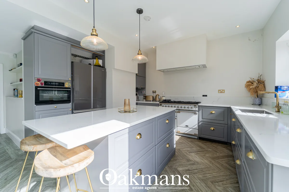 Modern fitted kitchen with grey cabinetry, white worktops, central island with seating, stainless steel range cooker and
