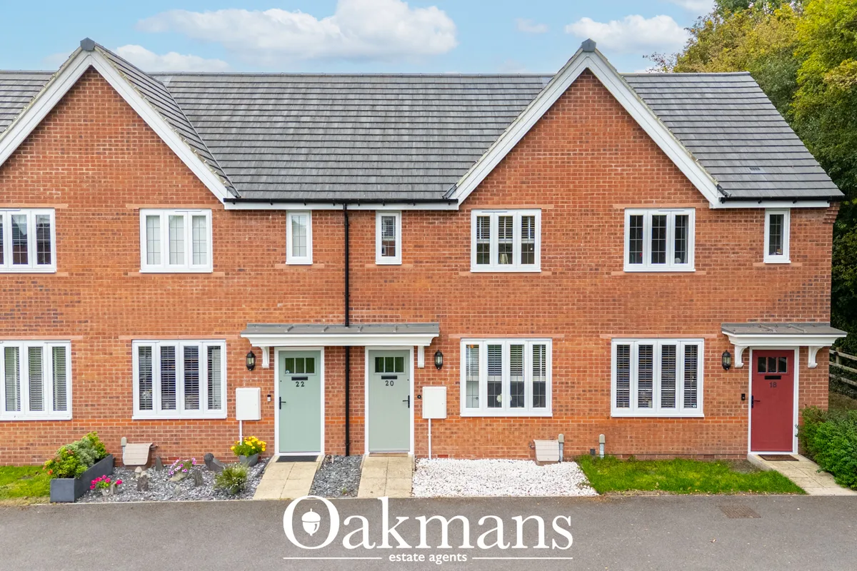 Modern red brick terraced houses with white trim, dual pitched roofs, gabled ends, and neat front gardens