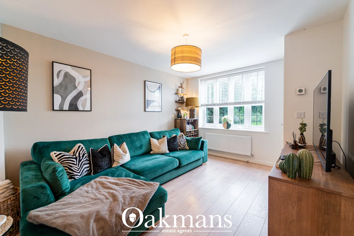 Contemporary living room with teal velvet corner sofa, patterned cushions, wooden TV unit with cactus décor, pendant cei