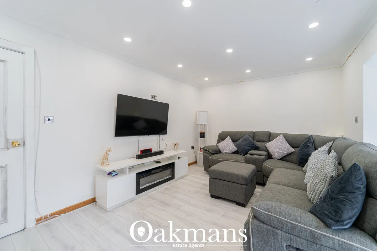 Spacious living room with large grey corner sofa, wall-mounted TV above white media unit with electric fireplace, recess