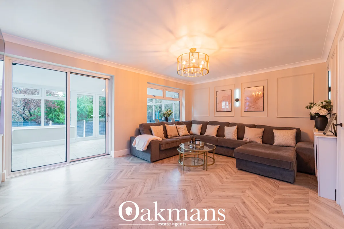 Spacious living room with brown corner sofa, herringbone wood flooring, peach walls, ceiling pendant light, framed artwo