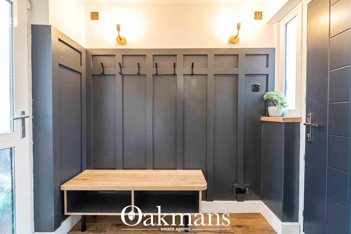 Contemporary entrance hallway with dark panelled walls, wooden bench seating, built-in storage lockers with hooks, and g