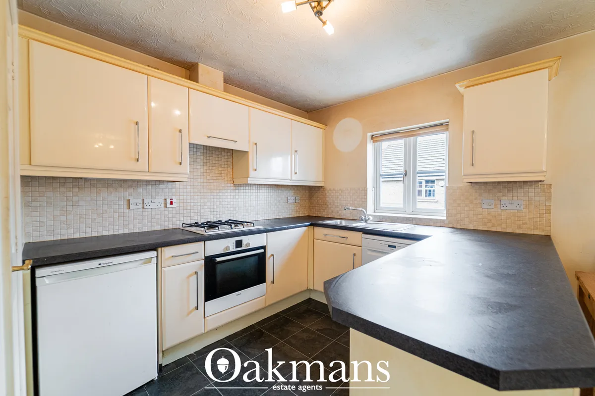 Modern fitted kitchen with cream and wood units, black granite worktops, tiled backsplash, gas hob, oven and breakfast b