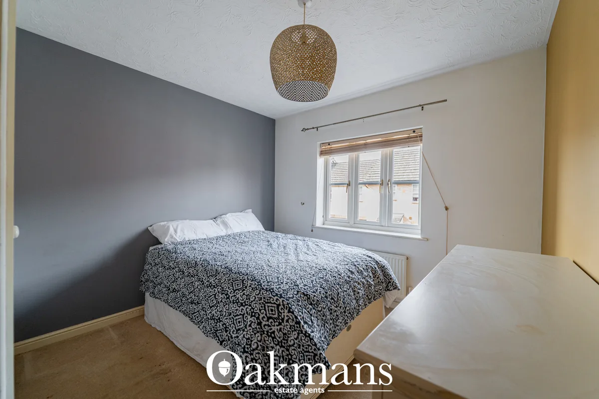 Bedroom with double bed, grey accent wall, patterned bedding, woven ceiling pendant light, and window with shutters