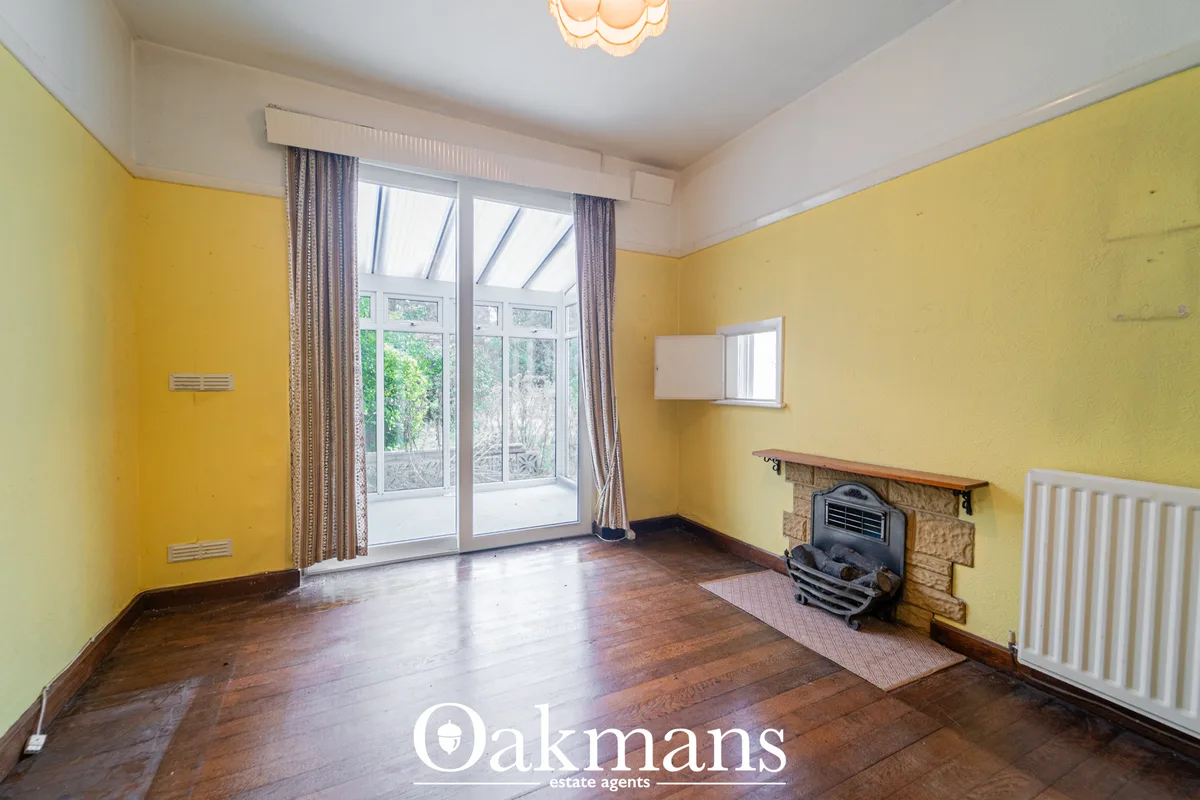 Bright yellow living room with dark wood flooring, fireplace with black stove, French doors to garden, white radiator an