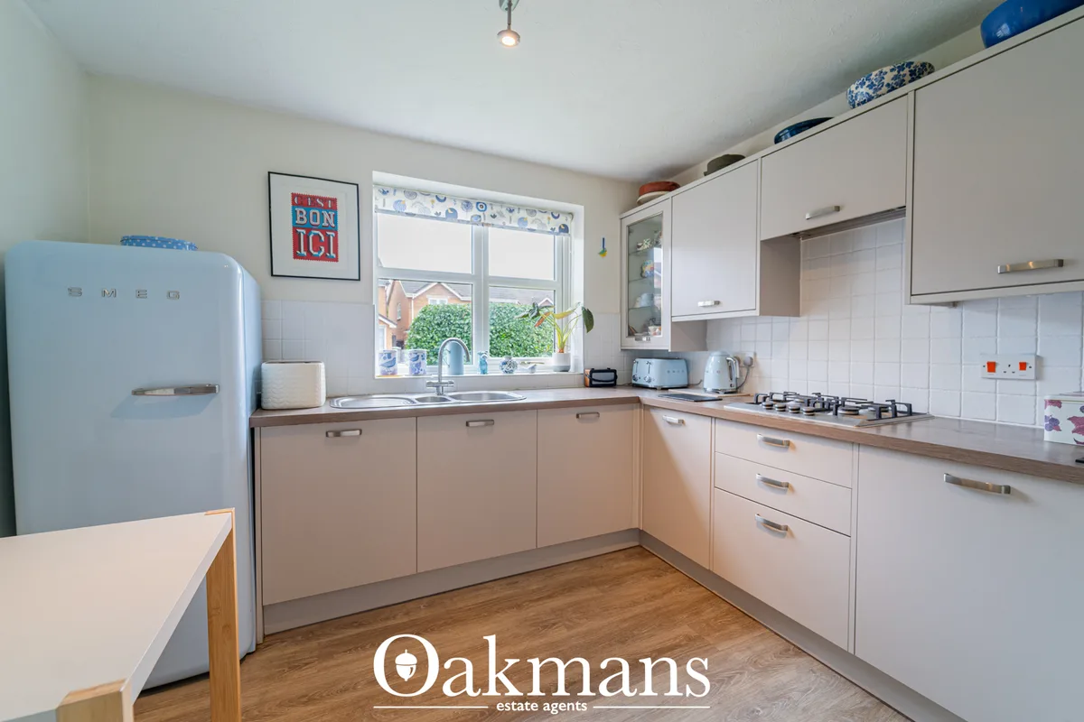 Modern fitted kitchen with cream and beige units, wooden worktops, gas hob, window overlooking garden, retro blue fridge