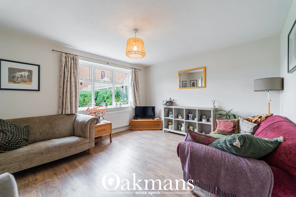 Spacious living room with two sofas, large windows overlooking garden, wooden flooring, pendant light, and built-in stor