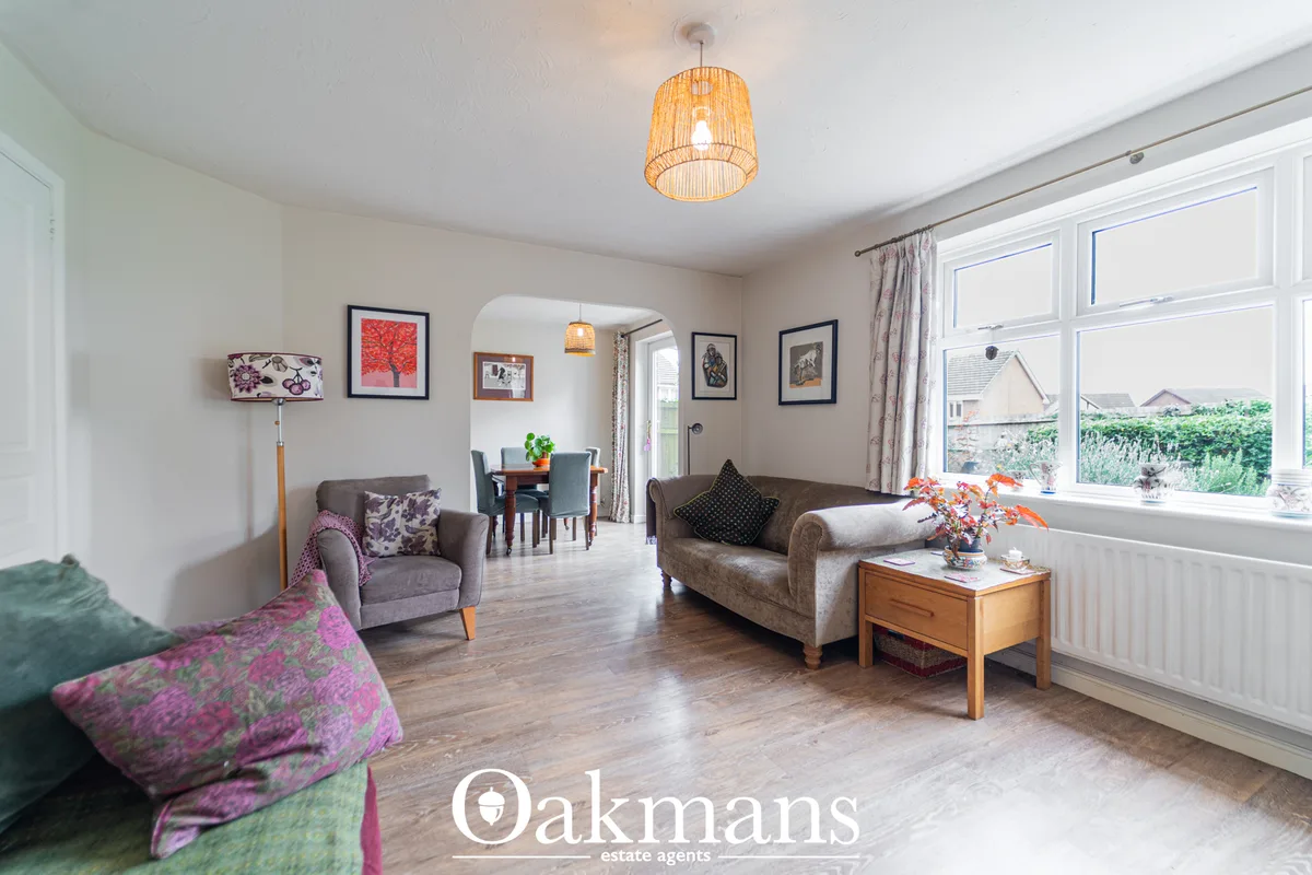 Spacious living room with grey upholstered sofa and armchair, wooden coffee table, framed artwork, wicker pendant light,