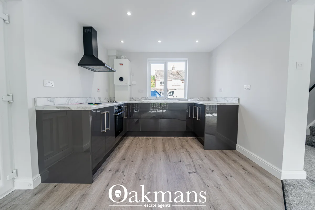 Modern fitted kitchen with dark grey gloss cabinetry, marble worktops, black range hood, integrated appliances and wood-