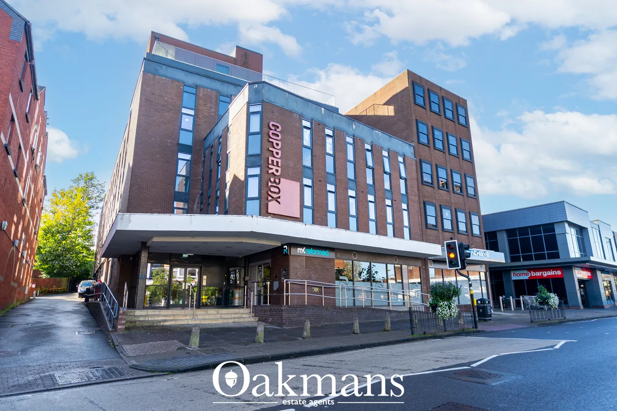 Modern mixed-use building with brick and glass facade, ground floor retail units, residential apartments above, street v