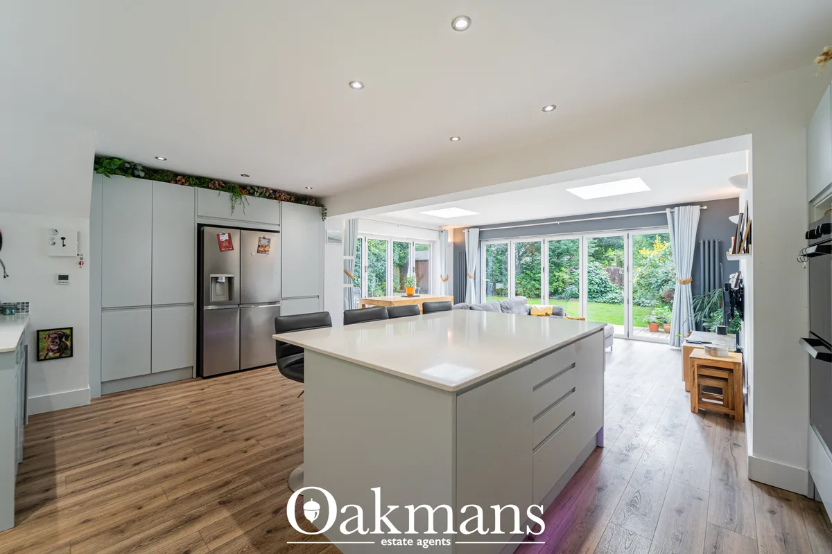 Modern kitchen with white cabinetry, stainless steel appliances, white island with breakfast seating, wood flooring, and
