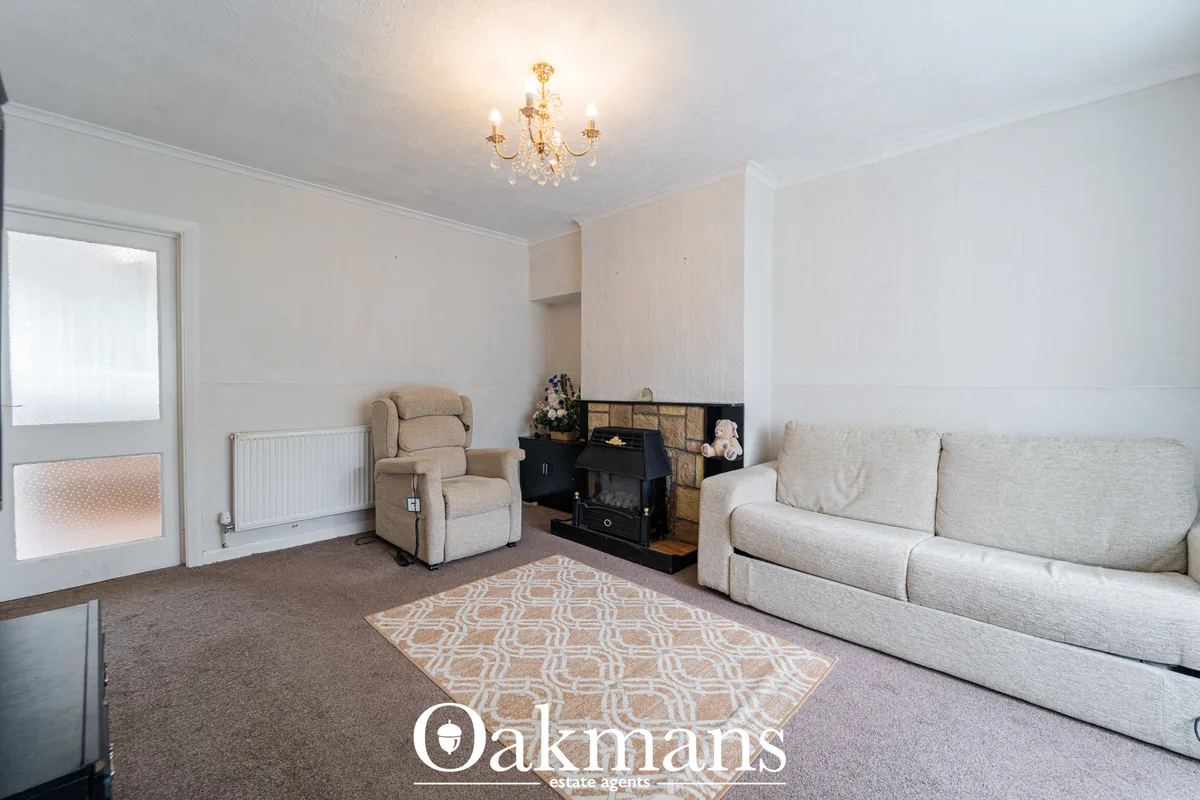 Spacious living room with cream sofa, beige armchair, geometric patterned rug, black wood burner with stone surround, ra