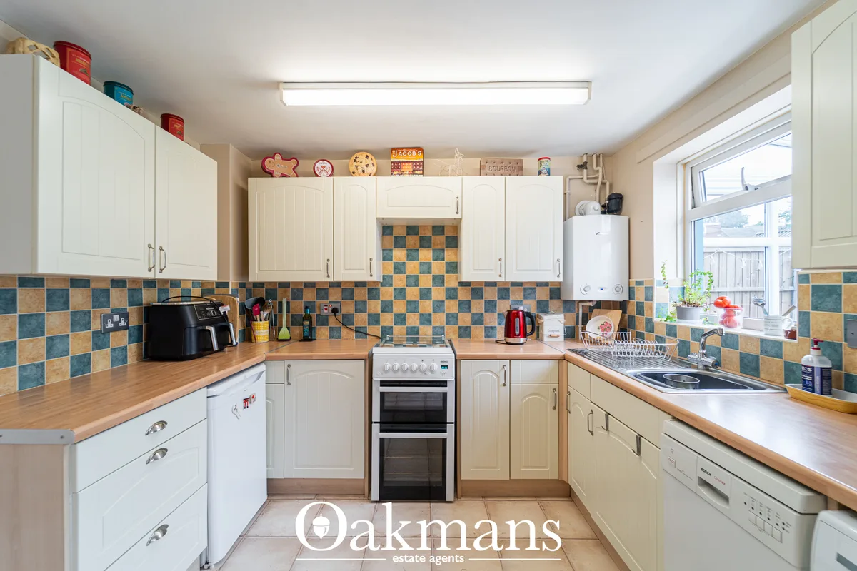 Modern fitted kitchen with cream cabinets, wooden worktops, blue and terracotta tiled splashback, double oven and large 