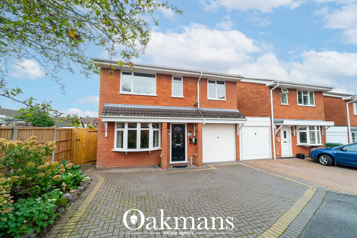 Red brick two-storey semi-detached house with white trim, black entrance door, double garage, and brick paved driveway