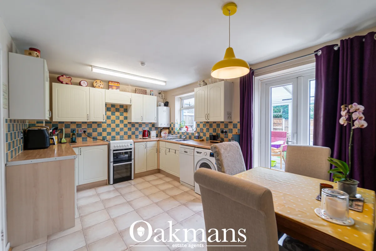 Modern kitchen with cream units, blue and orange checkerboard backsplash, wooden worktops, integrated appliances and bre