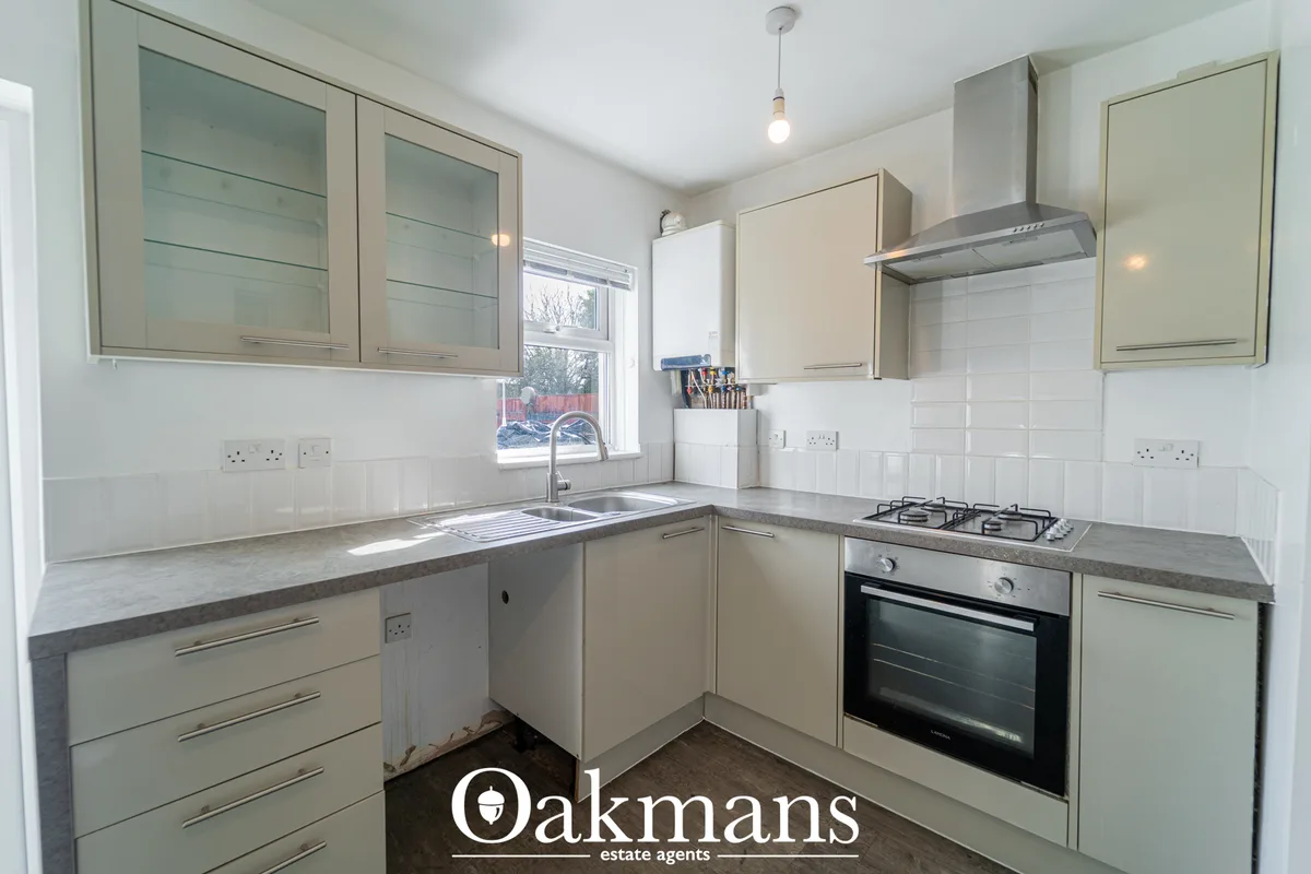 Modern fitted kitchen with cream units, grey worktops, built-in oven, gas hob, white subway tile splashback and stainles