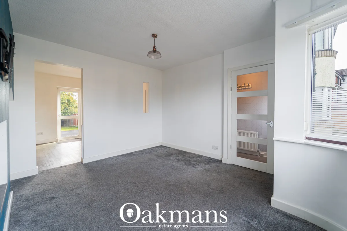 Spacious living room with grey carpet, white walls, pendant light fixture, built-in storage with glass doors, and views 
