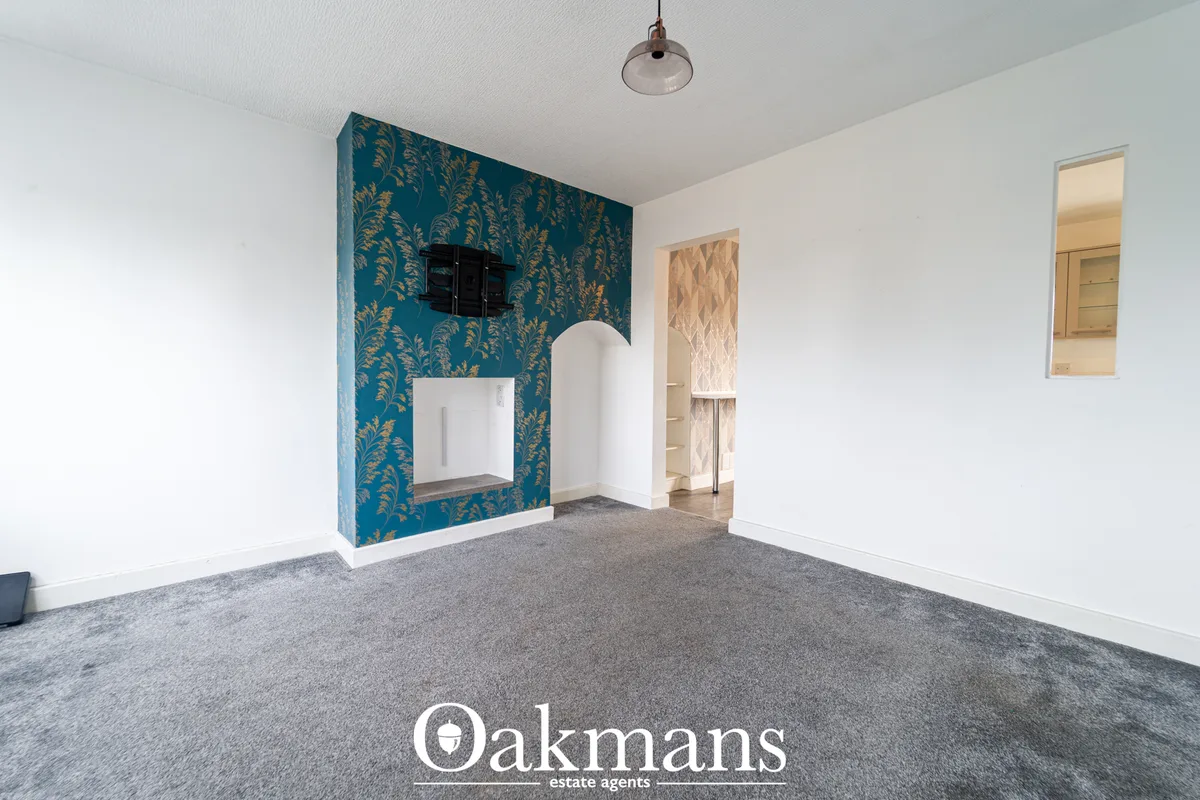 Spacious living room with teal patterned feature wall, white walls, grey carpet, TV mount, pendant light and doorways to