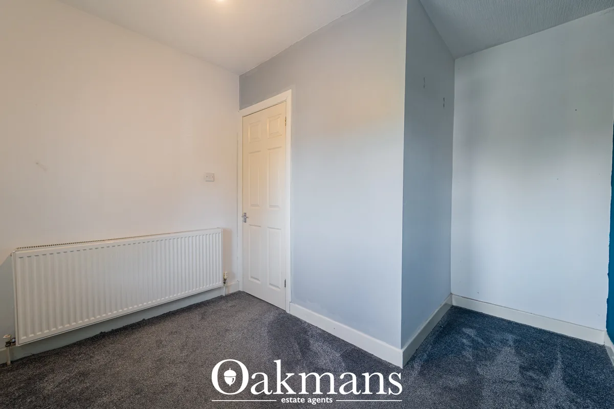 Bright hallway with white walls, cream radiator, grey carpet, white six-panel door and ceiling light