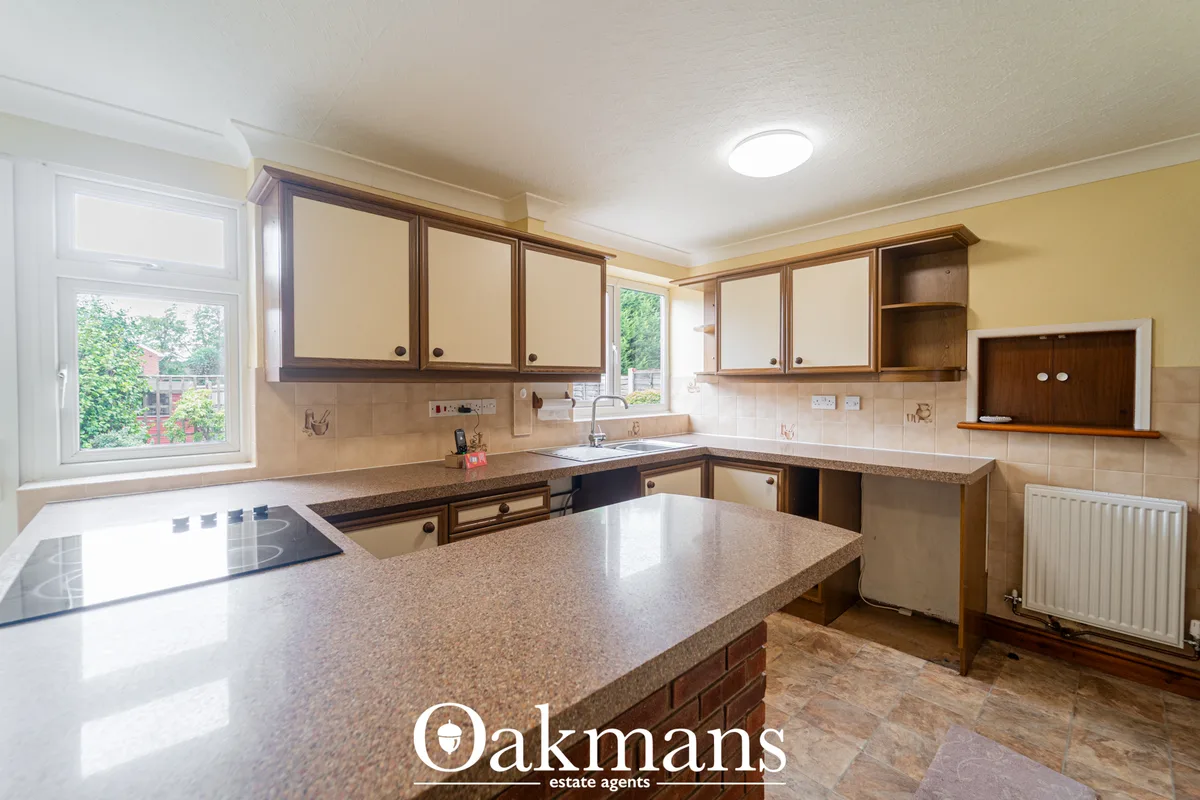 Spacious fitted kitchen with wooden units, granite worktops, induction hob, cream tile splashback and breakfast bar