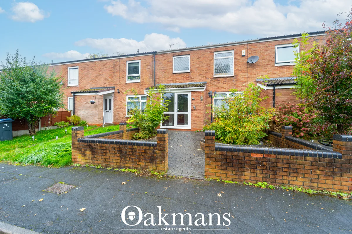 Red brick terraced house with white uPVC windows, front garden with brick planters and shrubs, paved entrance area