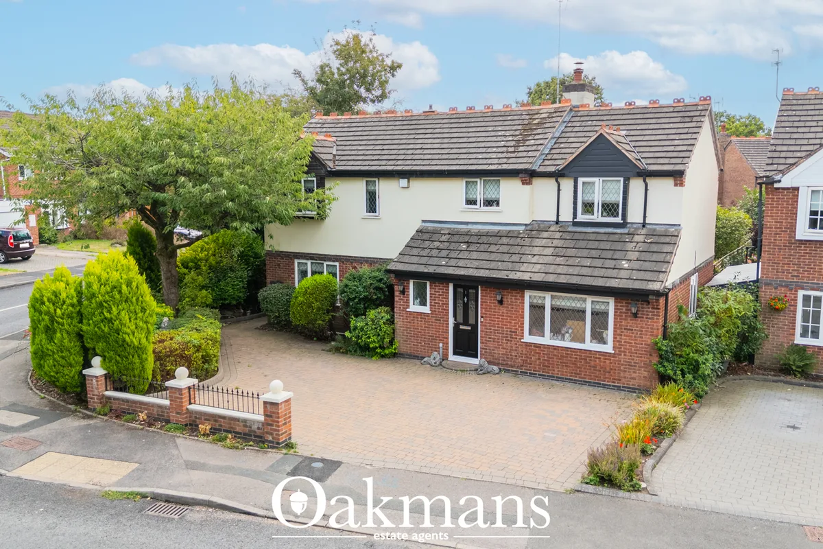 Two-storey brick-built semi-detached house with cream rendered upper storey, block-paved driveway, manicured gardens and