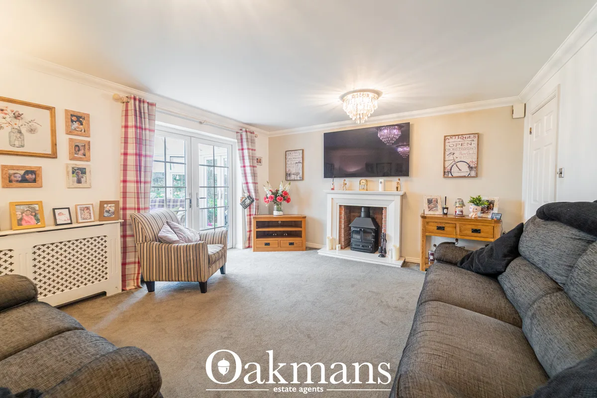 Spacious living room with grey upholstered sofas, fireplace with black stove, striped armchair, wooden furniture, framed