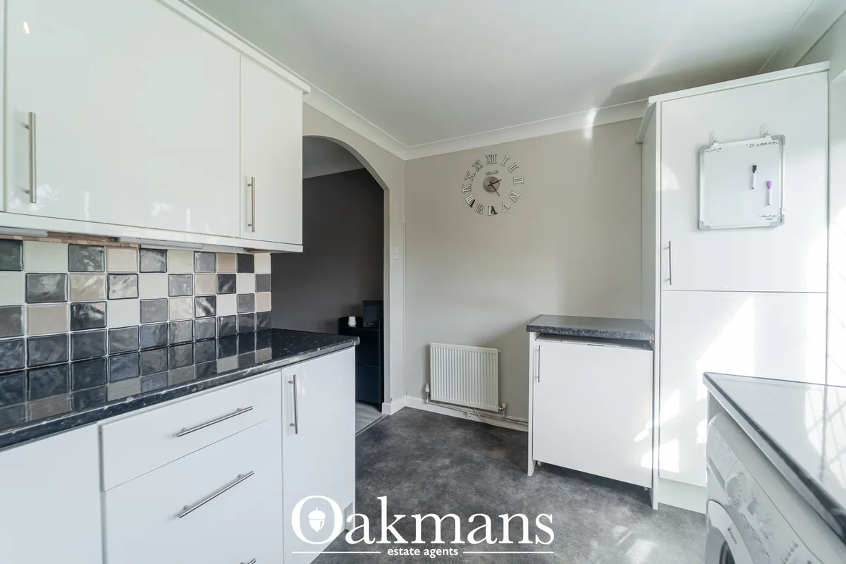 Modern fitted kitchen with white gloss units, dark granite worktops, dark grey and white tile splashback, stainless stee