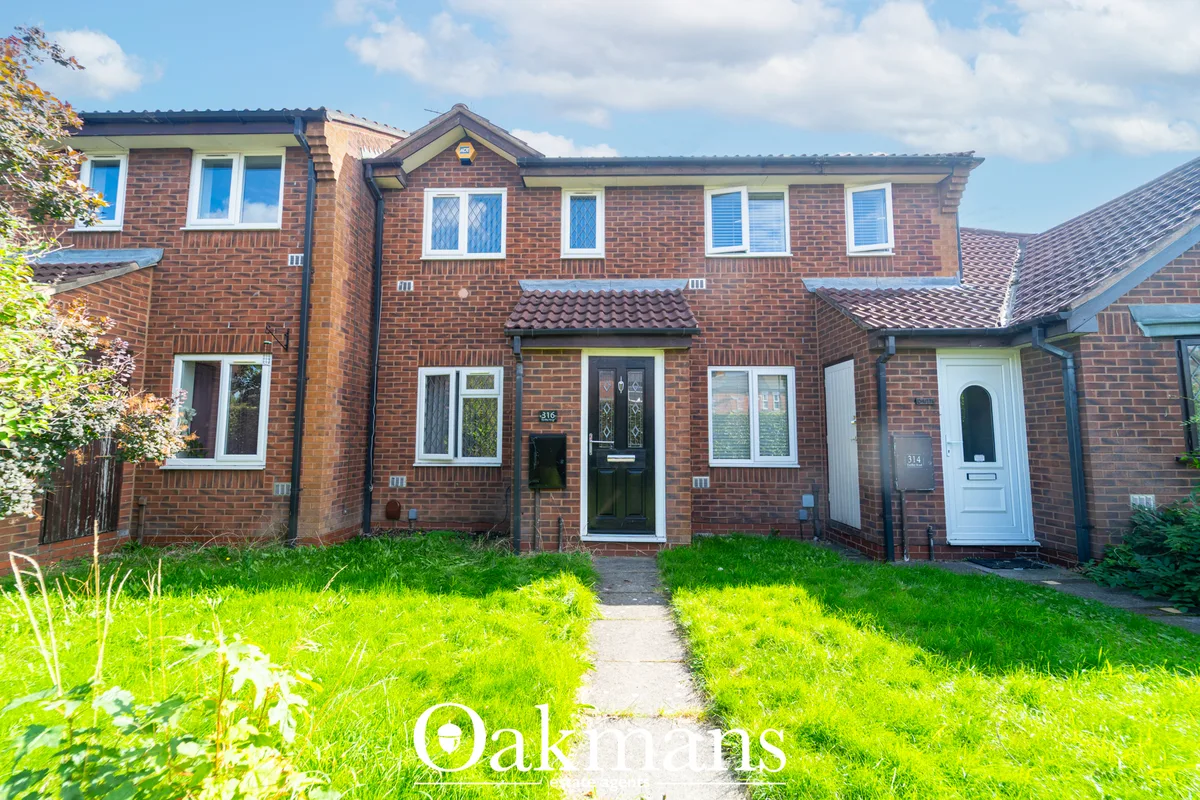 Red brick terraced house with white-framed windows, black front door, pitched roof and manicured front garden with pathw