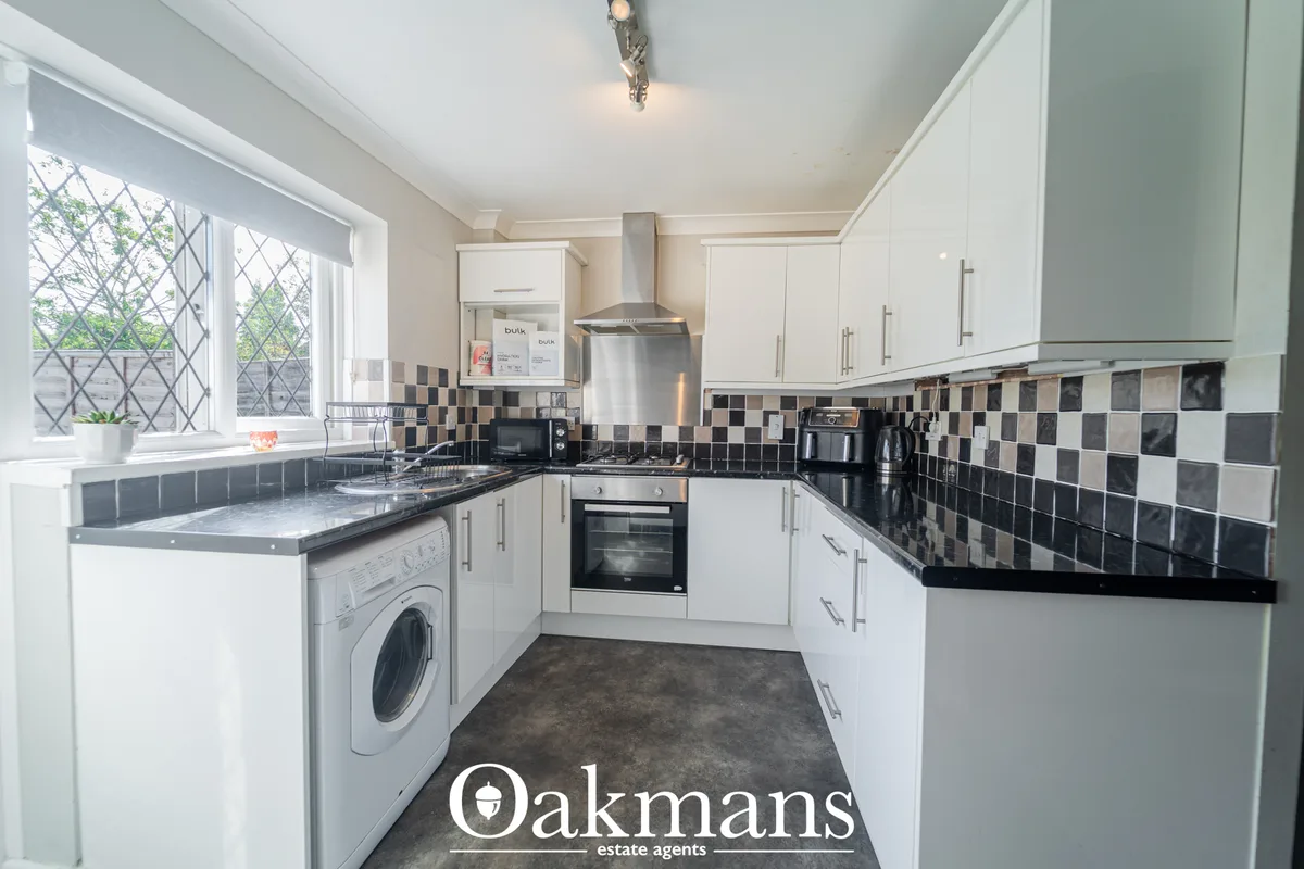 Modern fitted kitchen with white units, black granite worktops, black and white checked tile backsplash, integrated appl
