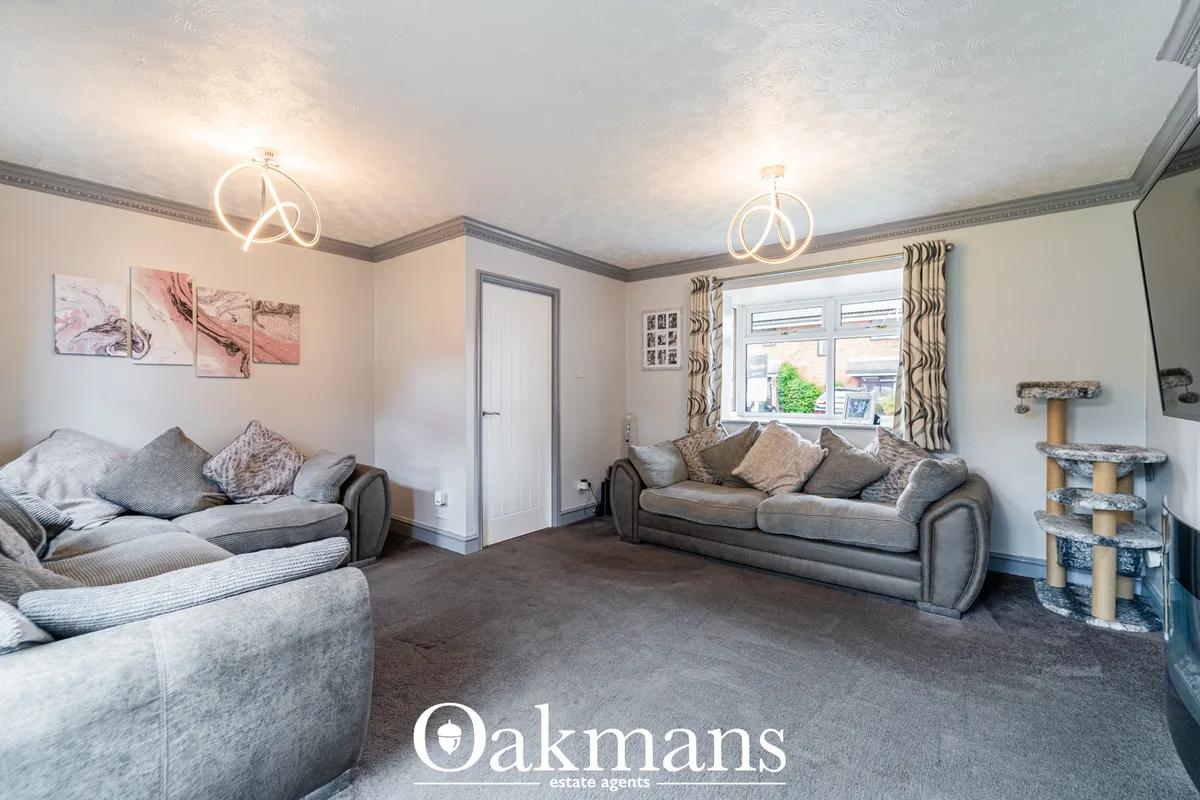 Spacious living room with grey fabric sofas, patterned cushions, modern ceiling lights, artwork, bay window with pattern