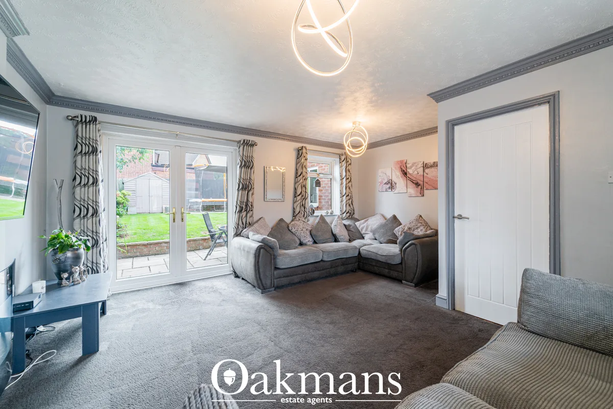 Spacious living room with grey corner sofa, patio doors to garden, patterned curtains, neon ceiling lights and contempor