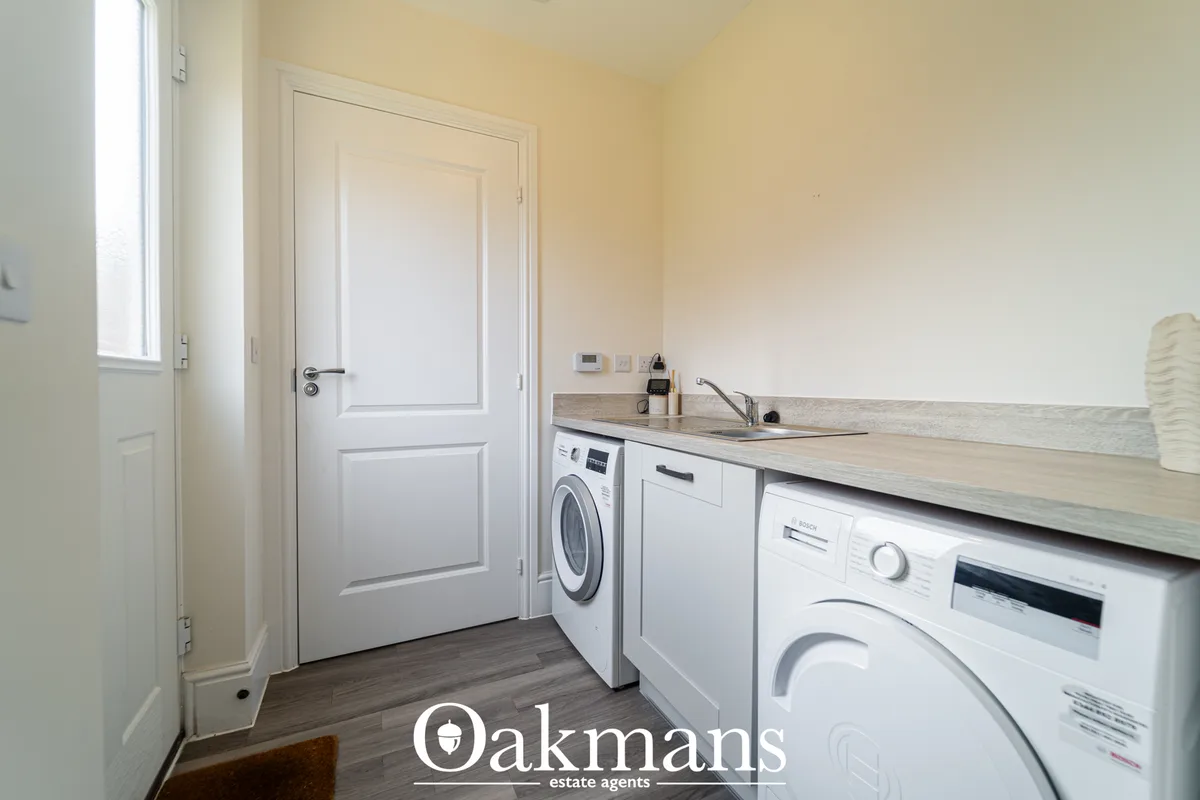 Modern utility room with white fitted units, wooden worktops, sink, integrated dishwasher and washing machines