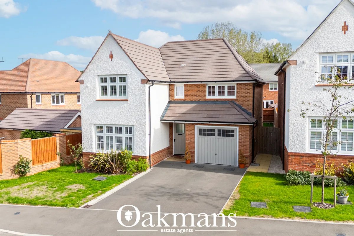 Modern brick and render detached house with pitched roof, driveway, grey garage door, manicured front garden and neighbo