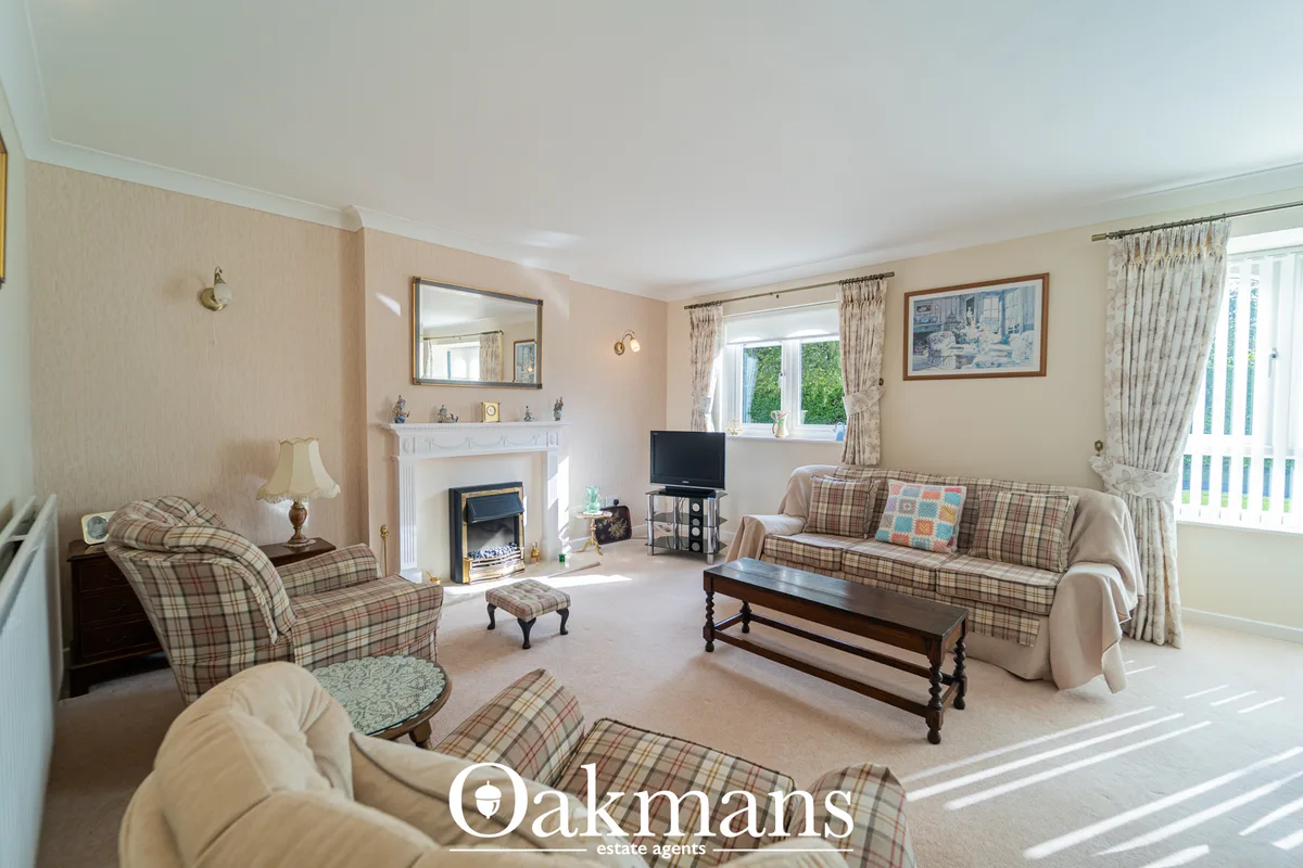 Bright living room with plaid upholstered furniture, fireplace with white mantel, flat-screen TV, wooden coffee table an