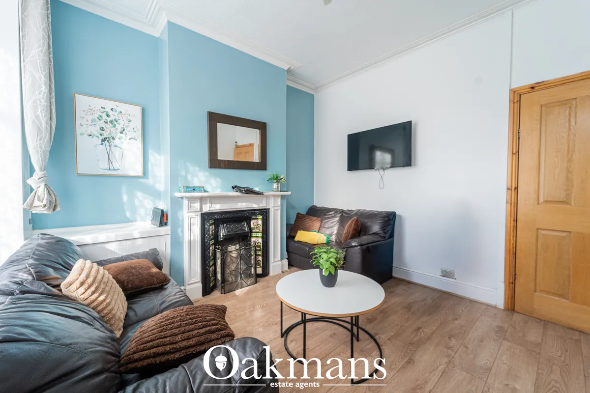 Living room with turquoise accent wall, black leather sofa, white fireplace, flat-screen TV, wooden coffee table with po