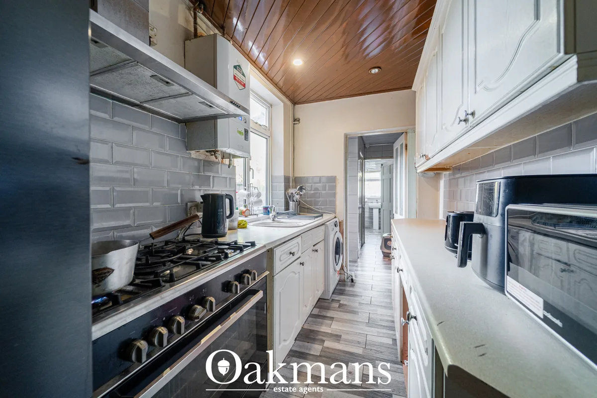 Modern galley kitchen with white cabinetry, black range cooker, grey subway tile splashback, wooden ceiling, and stainle