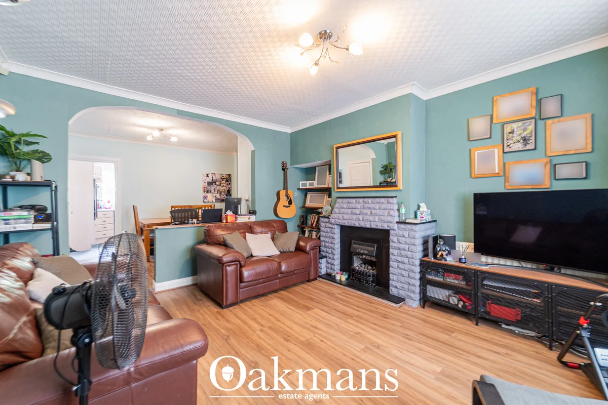 Spacious living room with turquoise walls, leather sofas, fireplace with grey brick surround, wooden flooring, TV, and g