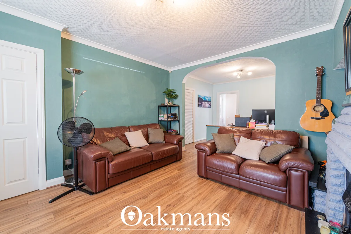 Spacious living room with turquoise walls, white ceiling, two burgundy leather sofas with scatter cushions, wooden floor