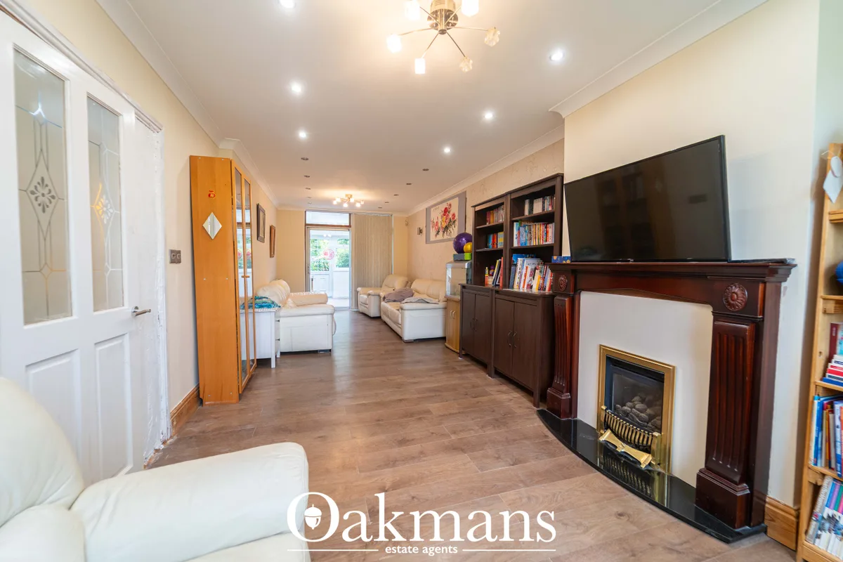 Spacious living room with cream walls, wooden flooring, fireplace with mahogany surround, flat-screen TV, bookshelves, c