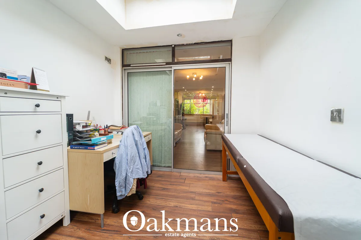 Bright hallway with wooden flooring, white storage unit, desk area, and glazed sliding doors opening to living space